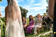 At the Tourterelle Inn in New Haven, Vermont, a grandmother gazes affectionately at the bride and groom as they exchange vows outdoors on a sunny lawn