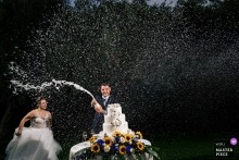 At a wedding in Recanati, during the cake moment, the groom exuberantly sprays champagne as his wife looks on nearby. This lively scene captures the joy and celebratory spirit of the occasion.