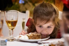 At a reception venue in Krakow, Malopolskie, a little girl begins her dessert by licking the plate. This endearing moment adds a touch of kid fun to the festivities.