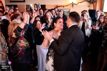In Trieste, Italy, the bride and groom share their romantic first dance, surrounded by watching wedding guests and soft lighting.