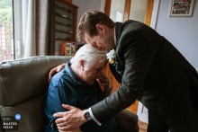An emotional groom embraces his ailing grandfather at a wedding in Wednesbury, UK, capturing a heartfelt and tender moment.