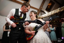 Joyful Newlyweds Rock Out with Inflatable Guitars at Vibrant Stratton Court Barn Celebration Bride and groom enthusiastically rock out with inflatable guitars, laughing and celebrating at Stratton Court Barn wedding reception.