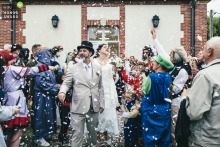   The bride and groom emerge from Boutencourt town hall with guests dressed in playful disguises, creating a festive and joyful atmosphere on the steps outside.