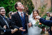 Groom in Worcestershire, West Midlands, smiling joyfully as colorful confetti is thrown over him outside the church after ceremony.