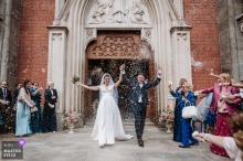Bride and groom exit ceremony in Turin city center as jubilant guests throw rice, celebrating their joyful, just-married moment.