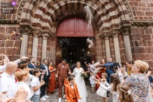 The Couple Walks Through Confetti And Petals At Église de Saint-Saturnin France Capturing Wedding Joy At the historic Église de Saint-Saturnin, France, a bride walks calmly through a storm of confetti and petals. The award-winning photograph highlights the photographer's skill at documenting the joyous moments of a wedding.