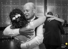 In Ille-et-Vilaine, Brittany, the parents of the bride embrace their daughter and her new husband during the reception dinner. The winning photograph highlights the photographer's ability to document the genuine, heartfelt emotions of the day.