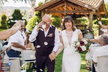 Ceremony exit in Lyon, France: Groom removing glasses after flower petals were thrown, one caught in his eye.
