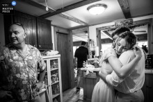 In Duluth, Minnesota, the photographer captures a warm black-and-white embrace between the bride and groom in the cabin kitchen after their ceremony, expertly preserving intimate post-wedding emotion.