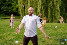 At The Intervale in Burlington, Vermont, the photographer captures a whimsical reception moment as a wedding guest juggles bean bags outside on the grass, showcasing skillful timing and playful scene observation.