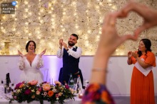 At domaine de Solomiac, the bride and groom applaud a guest, exchanging love with hand gestures shaped like hearts. The photographer’s creative vision captures this joyful, affectionate interaction during the celebration.