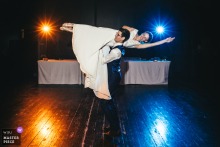 At Domaine de Montchevreuil, the groom spins the bride on his shoulder during their first dance, illuminated by colorful DJ lights. The photographer’s technical mastery captures dynamic motion and vibrant celebration.