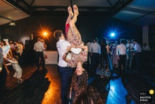 At Domaine de Montchevreuil, guests dance energetically to rock music as a man spins his partner upside down. The photographer’s technical expertise captures the excitement and motion of the lively wedding celebration.