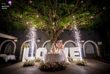 At Du Lac et Du Parc Grand Resort in Riva del Garda, Italy, the couple cuts their wedding cake amid a picturesque lakeside and fireworks backdrop, marking a memorable and elegant celebration moment.
