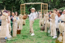 Château Grange Fort, Puy de Dôme Wedding: Boy Tosses Petals Down Aisle With Joy At Château Grange Fort in Puy de Dôme, a young boy with a playful smile enthusiastically tosses petals down the aisle, delighting wedding guests with his joyful energy and spontaneity.