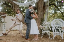 In Machemont, France, the bride and groom share a kiss at the end of the ceremony while the officiant makes a discreet yet funky exit with a large, playful stride in the background.