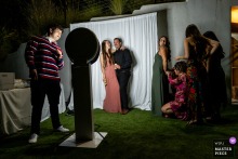 At Tivoli Italian Villa in Fallbrook, CA, wedding guests gather at the photo booth during the reception, striking poses and enjoying the opportunity for lighthearted photos as part of the celebration.