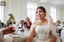 At Grand Hotel du Pont in Le Pont, Switzerland, the bride’s face shows deep emotion as she listens to a heartfelt speech. Someone gently hands her a tissue, capturing a touching and sincere moment during the celebration.