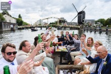 In Amsterdam, Noord Holland, the wedding party celebrates on a boat, cheering together as they glide along the city’s iconic canals. The scene captures festive energy and the unique spirit of an Amsterdam wedding.