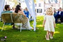 Little Girl Wanders In Mother’s Shoes At s-Hertogenbosch Noord Brabant Ceremony At a ceremony location in 's-Hertogenbosch, Noord Brabant, a young daughter playfully wanders on the grass in her mother’s bridal shoes. The sweet moment captures innocence and a child’s wonder on the wedding day.