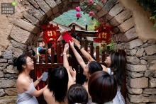 At a hotel in Taiyuan, Shanxi, bridesmaids and friends playfully prevent the groom from entering the procession, adding laughter and anticipation to the festivities.