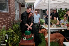 At a backyard reception in Melbourne, Victoria, a curious puppy fixates on the wedding cake, delighting guests with its adorable interest in the dessert at the lively party.