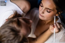   An overhead angle captures the stillness and trust as bridal makeup is applied in the hotel, highlighting the intimate focus and care that begins the wedding morning in Massachusetts.