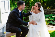   Seated together outside at Hacienda La Masía in Linares, Jaén, Spain, the groom gently wipes tears from the bride’s face in a peaceful, intimate scene away from the main festivities.