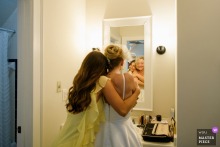   At Tranquil House Inn in Manteo, North Carolina, a bridesmaid offers a heartfelt embrace to the bride as they prepare together for the ceremony.