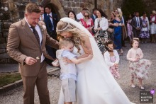   Relaxed happiness at Danby Castle in North Yorkshire as the bride warmly embraces the couple's son following their ceremony, surrounded by loved ones.