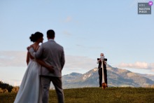   At the reception venue in Switzerland, the groom’s father plays the alphorn for the newlyweds, with majestic mountains forming a breathtaking backdrop for this musical performance.