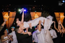   The bride, elevated in arms at the Four Seasons Hotel in Istanbul, laughs with delight as loved ones watch during a playful and memorable dance.