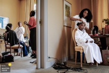   At Domaine de Divonne, La Grand Hotel in Divonne Les Bains, France, the bride and her daughter enjoy a special moment getting their hair and makeup done together in the hotel room.