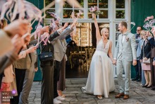   At Schloss Heeren in Kamen, Germany, the bride radiates energy and excitement as she leaves the venue following her civil wedding ceremony, surrounded by her husband, and joyful friends and family.