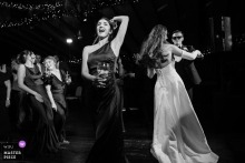   At Segrave Barns in Ireland, the bride and groom dance together while a bridesmaid takes center stage, and two more bridesmaids laugh together, adding liveliness to the celebration.