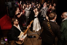   Guests dance joyfully with the happy couple as a live band performs at Nell’s Kampus in Manchester, England, filling the venue with music, celebration, and unbridled energy.