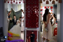   While the bride puts on makeup at home in Shanxi, her friends tidy up the wedding display rack nearby, with wedding photos cleverly displayed between the two bustling rooms.