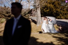 Wind turns the veil battle into theater at Greenbriar Inn in Boulder, Colorado, where the bride and bridesmaid wrestle the fabric as the groom waits in the foreground.