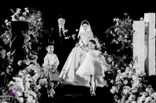 At China Kaifeng Wenlan Hotel, the flower girl joyfully scatters petals as the bride and groom enter, her bright motion adding childlike exuberance to the ceremony.