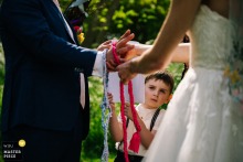 From the ceremony location in London, England, the young usher watches the bride and groom tie the knot, his steady gaze lending the scene a childlike solemnity.