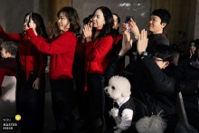 Guests clap at the hotel in Fujian, China, while a dog watches from the edge of the scene, the animal’s calm curiosity offering a quiet comic counterpoint.