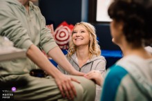 At The Sea Tea Theater In Hartford, Connecticut, A Bridesmaid Helps The Bride Prepare At The Sea Tea Theater in Hartford, Connecticut, a bridesmaid looks up at the bride while helping her get ready, a small gesture full of loyalty and wonder.