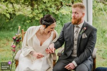 At Kanuhof Zur Ems in Lingen, Emsland, Germany, the bride and groom's reactions during the speech shift between delight and gravity, their faces carrying the room's emotional weather.
