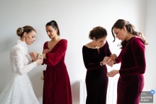 At Château du Souzy in France, the bride’s witnesses fasten bracelets of fresh flowers, their careful hands and blooming detail adding tenderness, ritual, and a handmade intimacy to the scene.