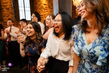 Guests holding hands and dancing at Auberge Saint-Gabriel in Montreal, Canada turn the reception floor into a small communal anthem, where movement, connection, and rhythm meet without pretense.