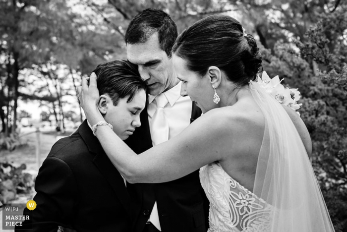 Foto von: <a href="https://www.wpja.com/contests/2016-q1-photography-contest/emotion/1842281"> Julie Ambos - Vereinigte Staaten </a> Key West Braut und Bräutigam umarmen Sohn bei der Hochzeit | Florida Hochzeitsfoto