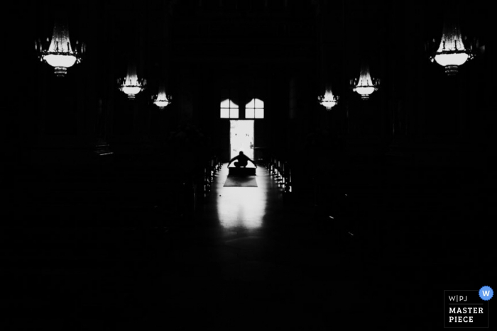 Black and white photo of the aisle hidden mostly in shadow with lights overhead by a Modena wedding photographer.