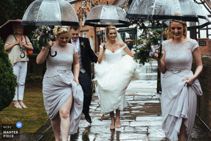 Photo: <a href="https://www.wpja.com/contests/2016-q3-photography-contest/weather/1900856"> Lyndsey Goddard - Royaume-Uni </a> La mariée et ses demoiselles d'honneur tiennent leurs robes comme elles se promènent sous la pluie avec des parapluies réalisées par un photographe de reportage de mariage à Londres.