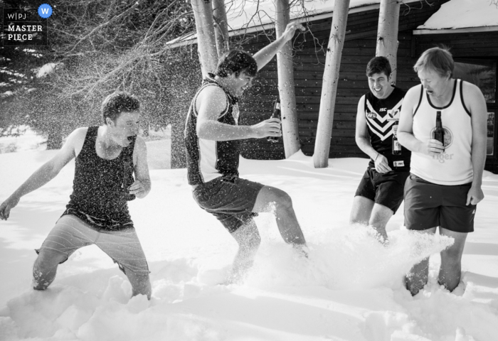 Photo de: <a href="https://www.wpja.com/contests/2016-q3-photography-contest/weather/1922786"> Kent Meireis - États-Unis </a> Photo noir et blanc de quatre hommes en short buvant de la bière à l'extérieur sous la neige, par un photographe de mariage du Montana.