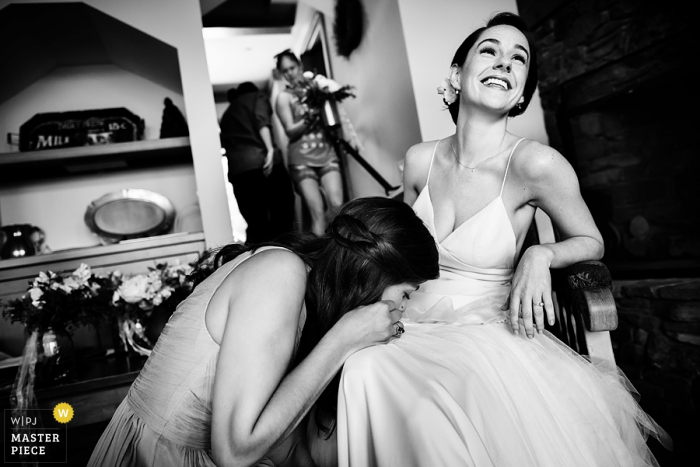 Photo by: <a href="https://www.wpja.com/contests/2016-q3-photography-contest/getting-ready/1904631">Megan Hannah - United States</a> Black and white photo of a woman fixing the bride's wedding dress by a Burlington, VT wedding photographer.